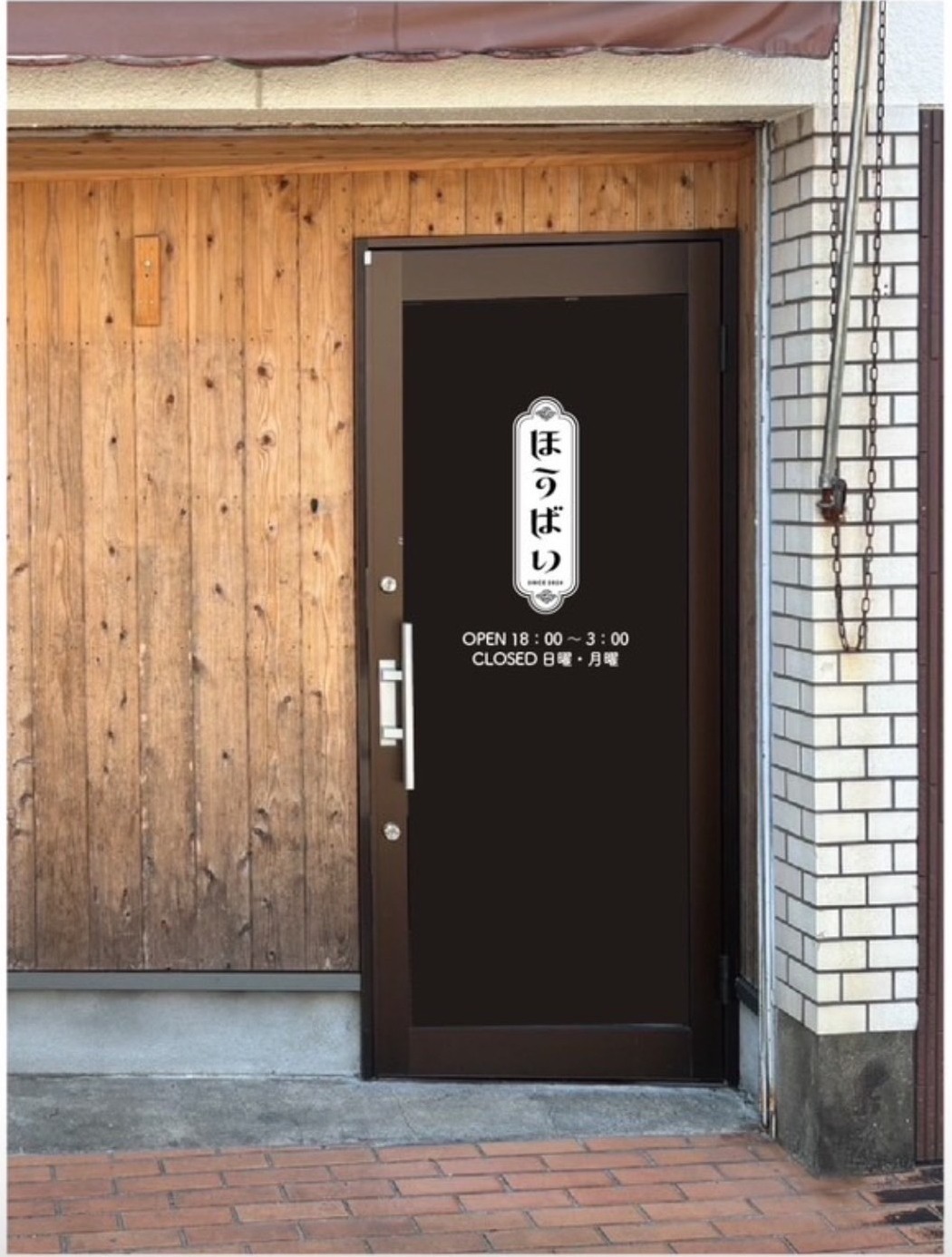 ほうばいの入口。木の壁に黒い扉